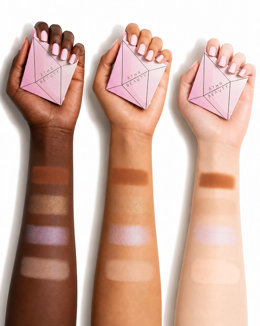 Three hands holding pink makeup products with color swatches on skin tones.