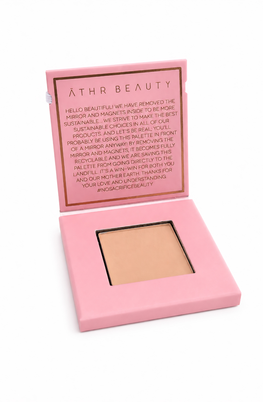 Open 'Athr Beauty' compact of the Desert Mirage Blurring Powder in the shade 'Citrine Sand' (a soft, warm beige with a banana-yellow tint) in pink case on white background