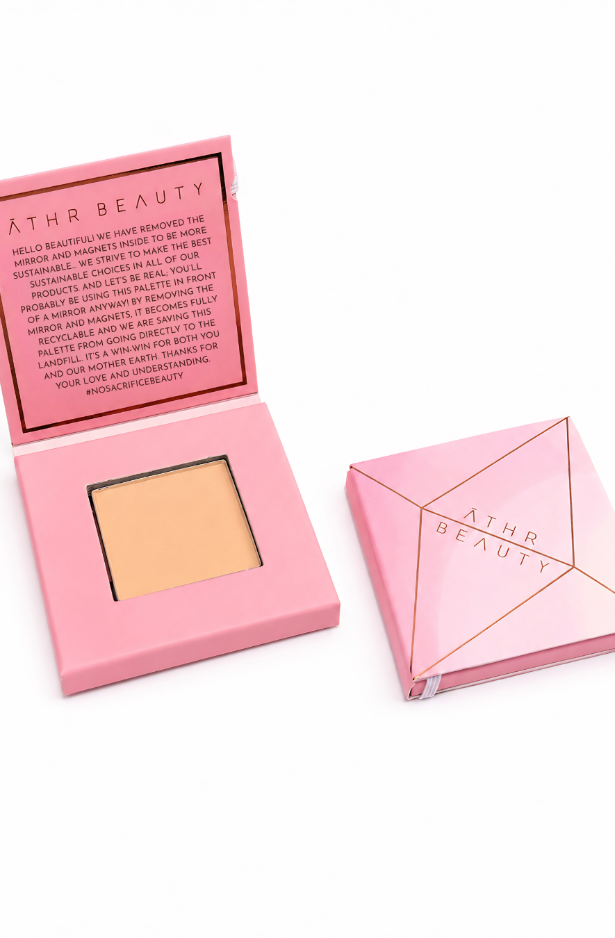 Athr Beauty makeup compact with open lid showing the Desert Mirage Blurring Powder in the shade 'Citrine Sand' (a soft, warm beige with a banana-yellow tint) product and closed case on white background