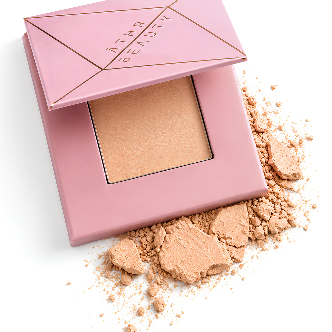 Open pink compact powder of Athr Beauty's 'Desert Mirage Blurring Powder' in the shade 'Citrine Sand' (a soft, warm beige with a banana-yellow tint) on a white background