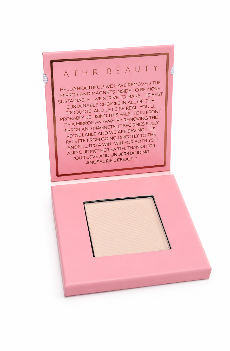 Athr Beauty pink makeup compact with an open lid showing the 'Desert Mirage Blurring Powder' in the shade 'Rose Mesa' (a soft, creamy beige with a subtle pink tint) on a white background