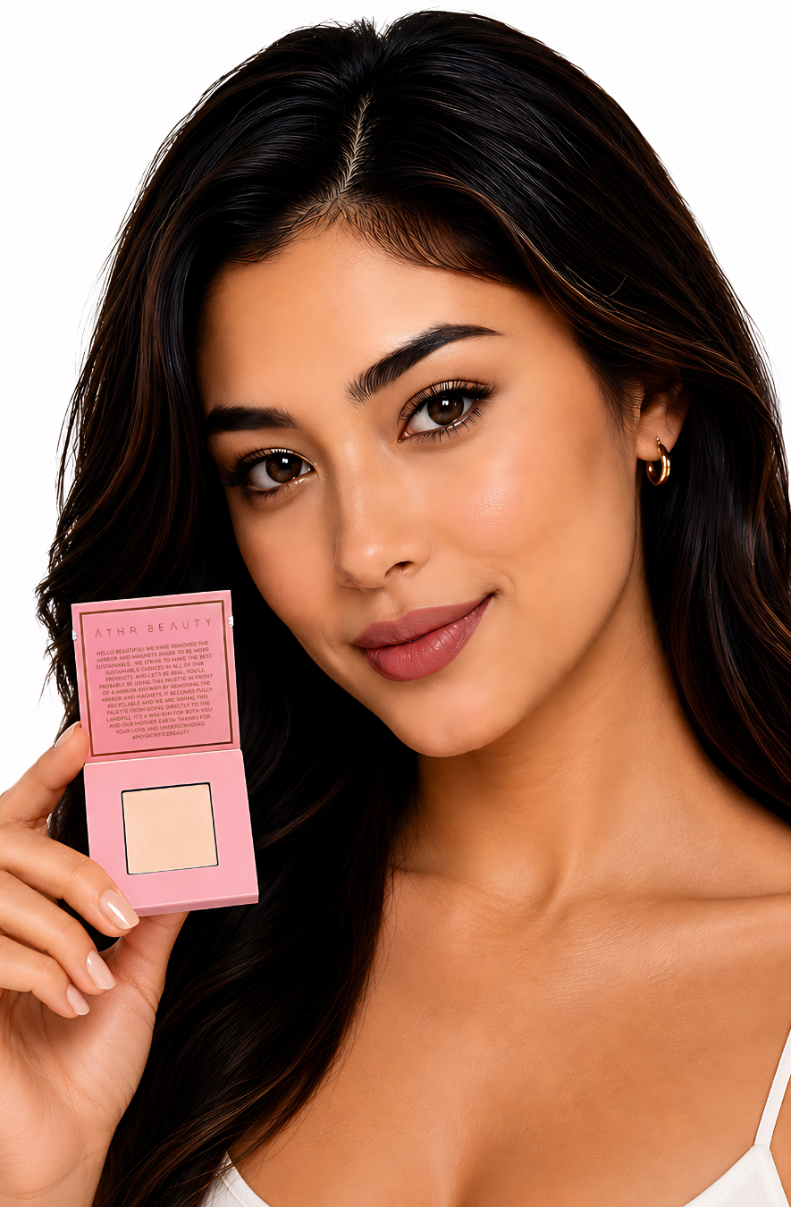 Model holding a pink powder compact of Athe Beauty's 'Desert Mirage Blurring Powder' with open lid in the shade 'Rose Mesa' (a soft, creamy beige with a subtle pink tint) with a white background
