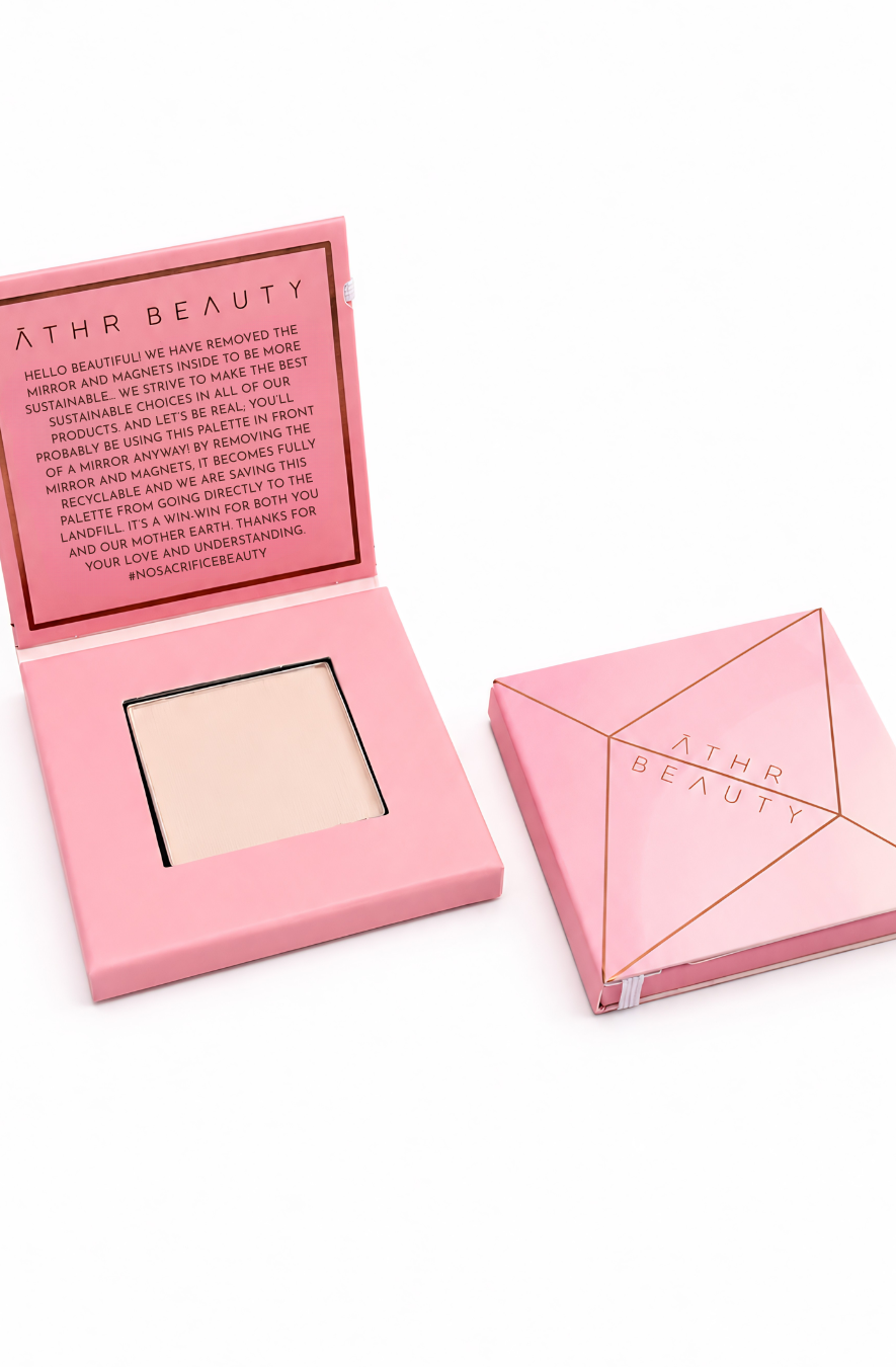 Athr Beauty's pink compact powder of the 'Desert Mirage Blurring Powder' with open lid showing powder in the shade 'Rose Mesa' (a soft, creamy beige with a subtle pink tint) and closed lid on a white background