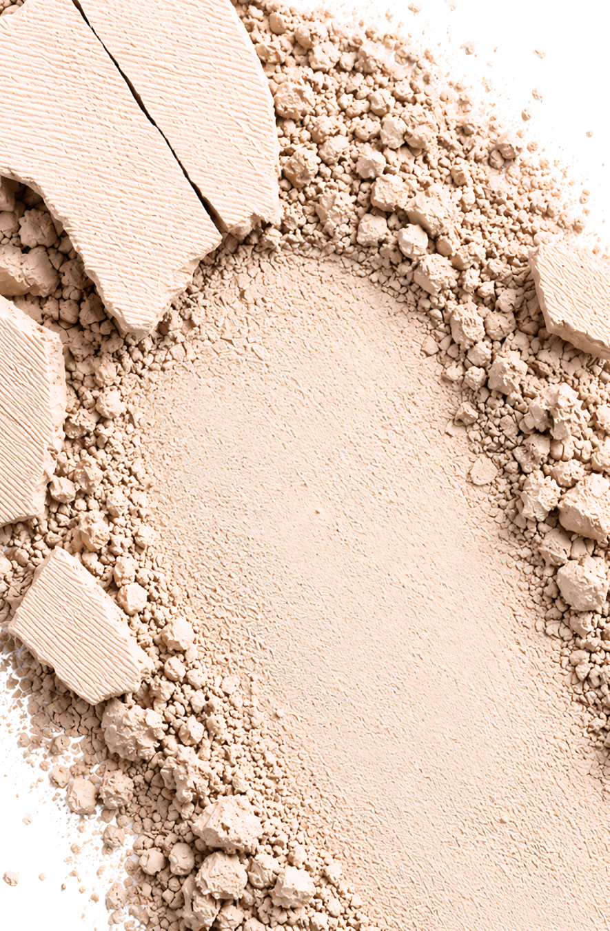 Close-up of Athr Beauty's 'Desert Mirage Blurring Powder' in the shade 'Rose Mesa' (a soft, creamy beige with a subtle pink tint) makeup powder with a few chunks on a white background