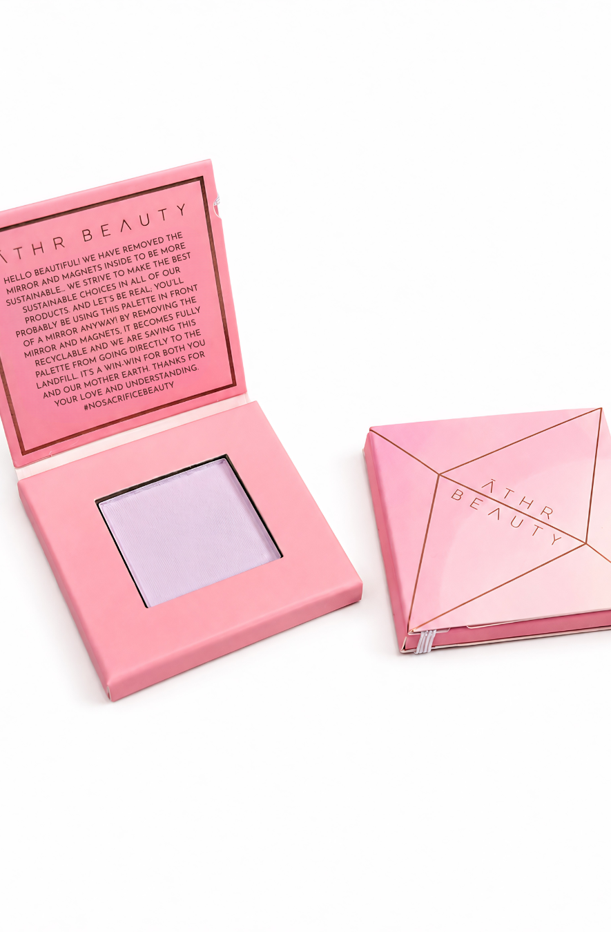 Pink 'Athr Beauty' makeup compact of the 'Desert Mirage Blurring Powder' in the shade 'Sagebrush' (a softly tinted lavender) on a white background