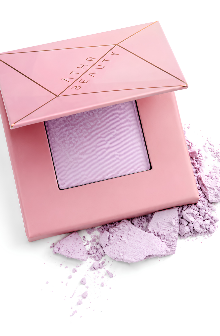 Pink makeup compact with lavender powder on a white background