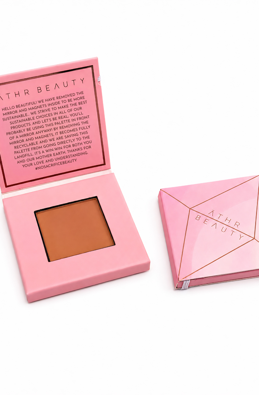 Pink makeup compact with brown powder and open lid showing brand text, on a white background.
