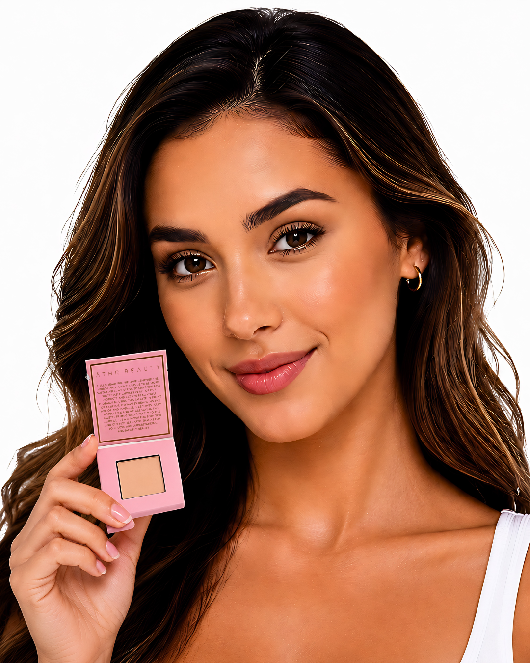 Model holding Athr Beauty's pink makeup compact of the 'Desert Mirage Blurring Powder' in the shade 'Citrine Sand' (a soft, warm beige with a banana-yellow tint) with a white background